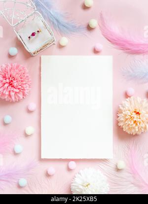 Blank Card near pastel flowers, pom-poms, feathers and ring in a gift box on pink Stock Photo