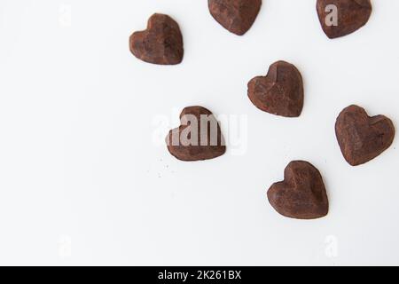 Chocolate candies with a truffle in the form of a heart on a white background, close-up. Place for an inscription. Stock Photo