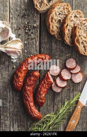 Smoked pork sausages. Sliced salami on wooden table. Stock Photo