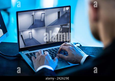 Security System Operator Looking At CCTV Footage At Desk Stock Photo