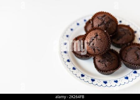 Chocolate muffins lie on a white plate with small hearts. Close-up, space for an inscription. Stock Photo