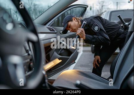 Woman cop using flashlight for car examining Stock Photo