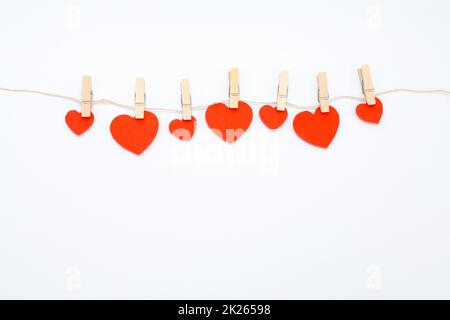Red hearts with clothespins hanging on clothesline isolated on white background. Stock Photo