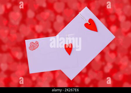 Happy Valentine or Mothers Day card template. 3D illustration of two envelopes with red hearts made of wood over abstract red background with hearts. Space for text design. Stock Photo