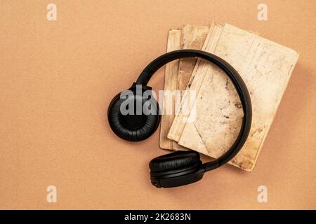 Top view of black headphones and books on cardboard background Stock Photo