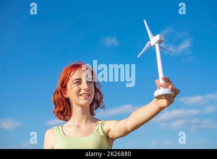 girl with wind turbine against blue sky Stock Photo