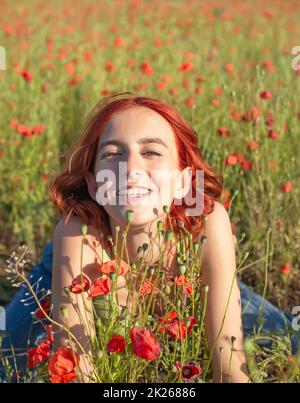 happy young girl with red hairs in poppy field Stock Photo