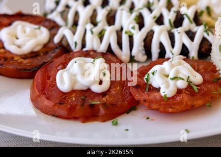 Fried souvlaki and grilled tomatoes. Stock Photo