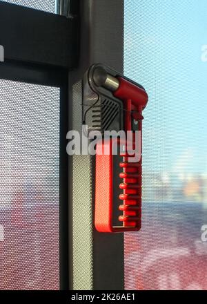 Red hammer, for breaking the window during emergency evacuation, on public bus window. Stock Photo