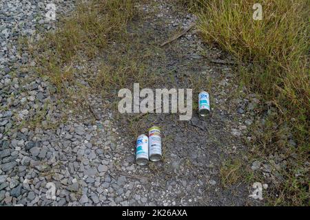 NEW ORLEANS, LA, USA - SEPTEMBER 17, 2022: Discarded paint cans left on the ground by vandals after tagging railroad car in Uptown New Orleans Stock Photo