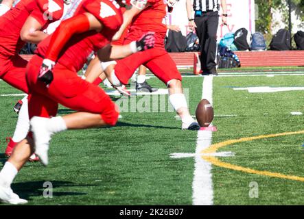 A high school football team kicking off with the official watching on the line during a game. Stock Photo