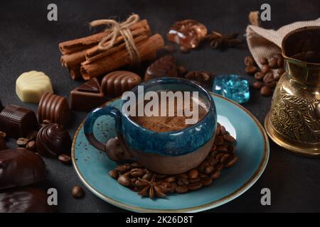 Coffee cup, beans, chocolate on old kitchen table Assortment of dark, white and milk chocolate sweets, zefir (zephyr). Spices, cinnamon. Stock Photo