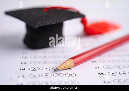 Graduation gap hat and pencil on answer sheet background, Education study testing learning teach concept. Stock Photo