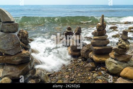 Pyramids of sea stones on the seashore .Entrance to the sea. Stock Photo