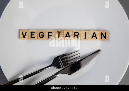 Top view white plate with vegetarian word against grey background top view, knife and fork on table health and food concept Stock Photo