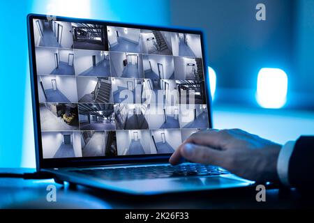 Security System Operator Looking At CCTV Footage At Desk Stock Photo