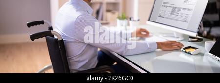 African Accountant With Disability Working On Computer Stock Photo