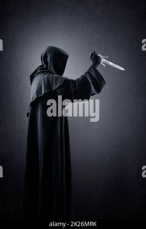 Hooded man with dagger in the dark Stock Photo