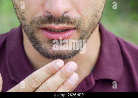 A bearded man covers his face with his palm. Stock Photo