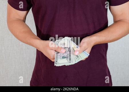 man holds a wad of dollars in his hands. US Dollars Stock Photo