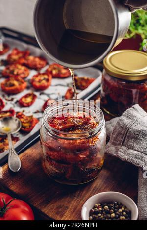 Coating of Sun Dried Tomatoes with Olive Oil in a Jar Stock Photo