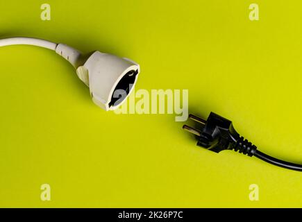 Black male plug and white female plug facing each other on a green background Stock Photo