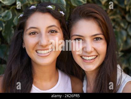 Two peas in a pod. Two young friends smiling happily while spending time outdoors. Stock Photo