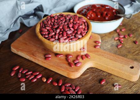 Raw and canned red kidney chilli beans in bowl on a rustic wooden table Stock Photo