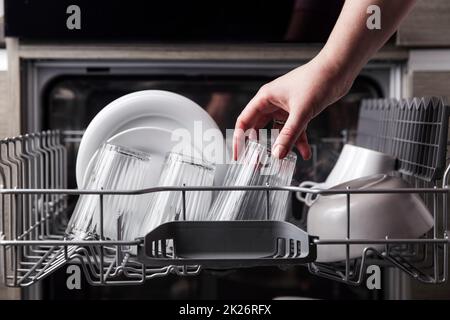 Open dishwasher with clean cutlery, glasses, dishes inside in the home kitchen Stock Photo