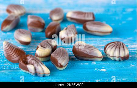 Chocolate candies sea shells on blue wooden background Stock Photo