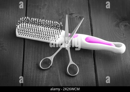 Hairdressing Scissors and massage comb taken from above on a black wooden backdrop Stock Photo