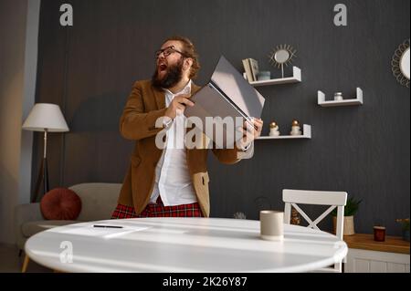 Mad guy in jacket throwing away his laptop Stock Photo