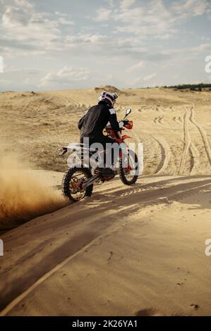 Professional motocross rider driving on sand dune Stock Photo