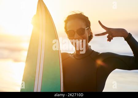 Come get your surf on. Portrait of a beautiful young female surfer posing with her surfboard at the beach. Stock Photo