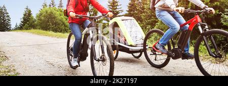 Family With Child In Trailer Riding Mountain Bikes Stock Photo