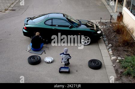 Someone changing from winter tires to summer tires in the yard of a residential area. Stock Photo