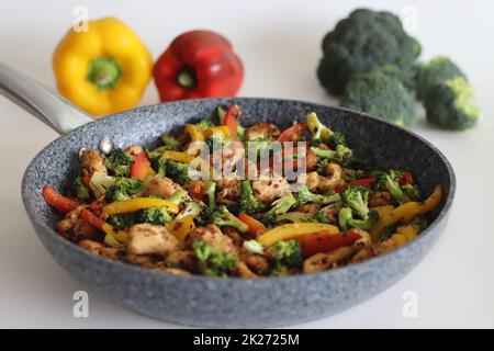 Stir fried vegetables with chicken in frying pan. Air fried chicken cubes tossed with sauteed bell peppers and broccoli. Shot along with broccoli bunc Stock Photo