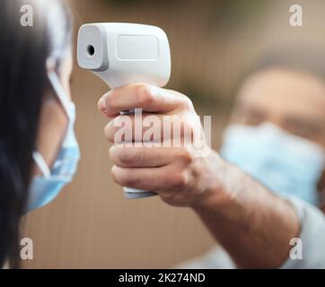 Temperature time. Cropped shot of an unrecognizable businesswoman wearing a mask and having her temperature taken while standing at the head of a queue in her office. Stock Photo