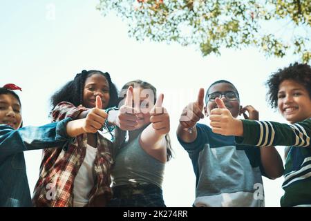 Our favourite summer camp by far. Shot of a group of teenagers showing thumbs up at summer camp. Stock Photo