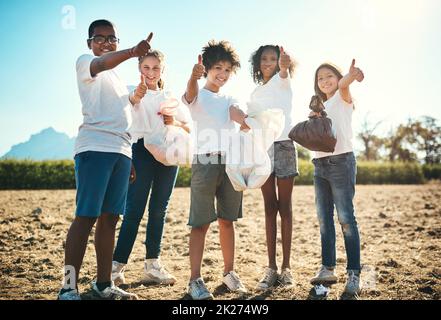 All green, all green, all good. Shot of a group of teenagers picking up litter off a field and showing thumbs up at summer camp. Stock Photo