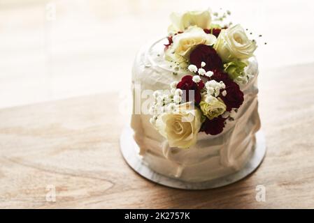 Perfect for life's sweetest moments. Still life shot of a beautiful wedding cake on top of a wooden surface. Stock Photo