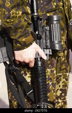 His trusty weapon. Cropped image of a soldier's hand holding a rifle. Stock Photo