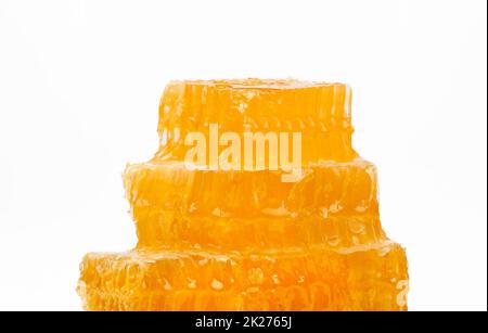 Close up stack of several fresh cut golden comb honey slices on plate isolated on white background, low angle, side view Stock Photo