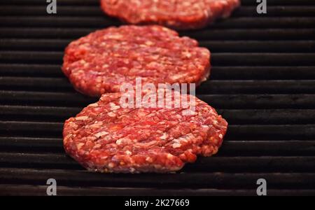 Raw beef burgers for hamburger on barbecue grill Stock Photo