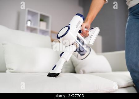Young Female Worker Cleaning Sofa Stock Photo