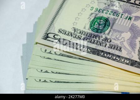 cistern of banknotes lies on a white table. Lots of dollars, a wad of dollars. Stock Photo