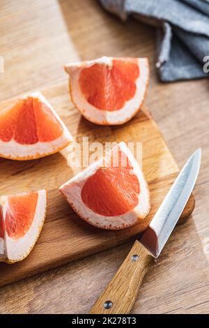 Sliced citrus fruit. Chopped fresh grapefruit on cutting board. Stock Photo
