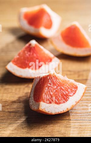 Sliced citrus fruit. Chopped fresh grapefruit on wooden table. Stock Photo