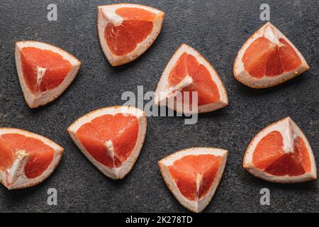 Sliced citrus fruit. Chopped fresh grapefruit on black table. Stock Photo