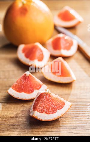 Sliced citrus fruit. Chopped fresh grapefruit on wooden table. Stock Photo